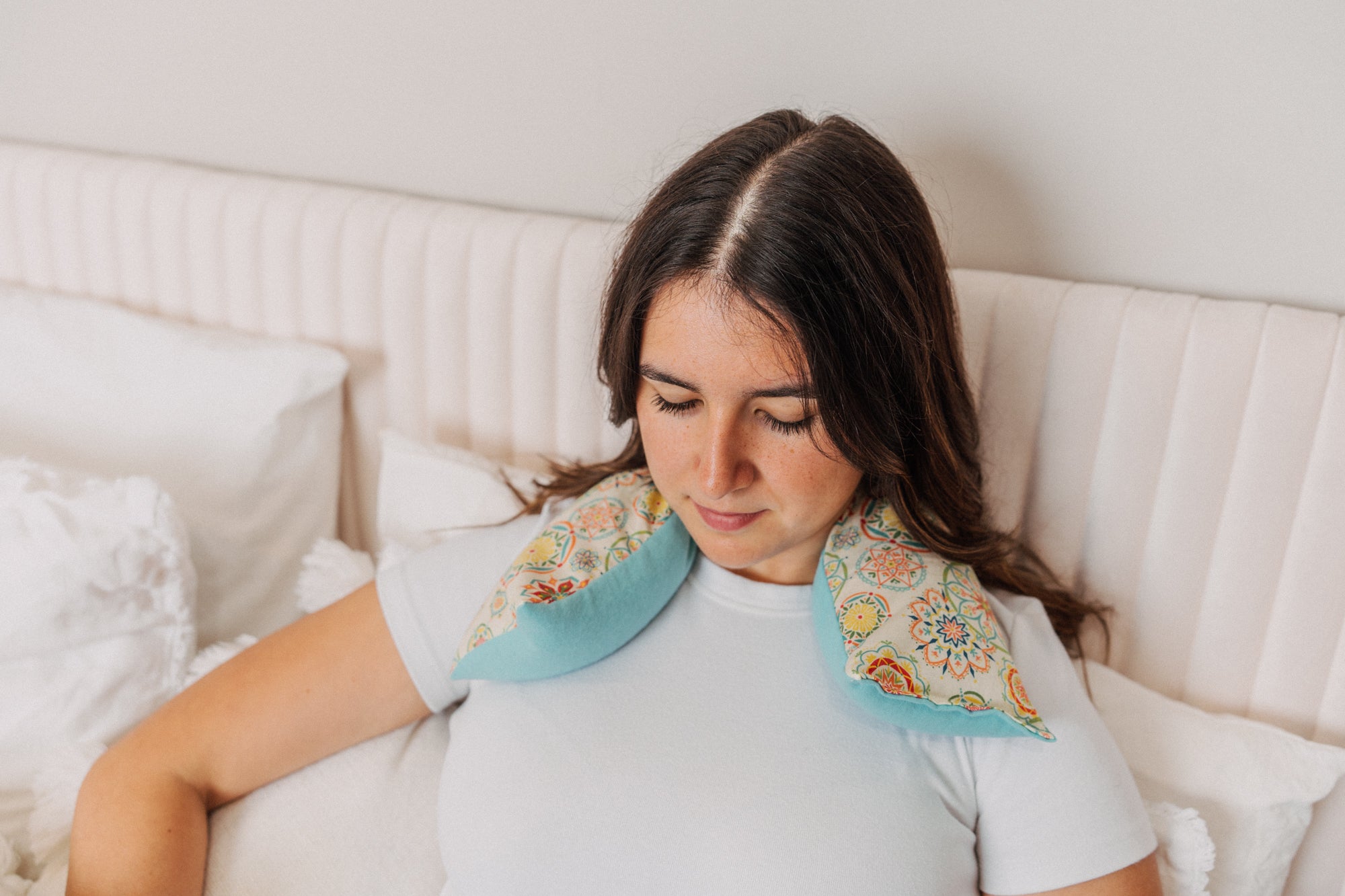 lady with cream medallion microwavable neck wrap on neck and shoulders