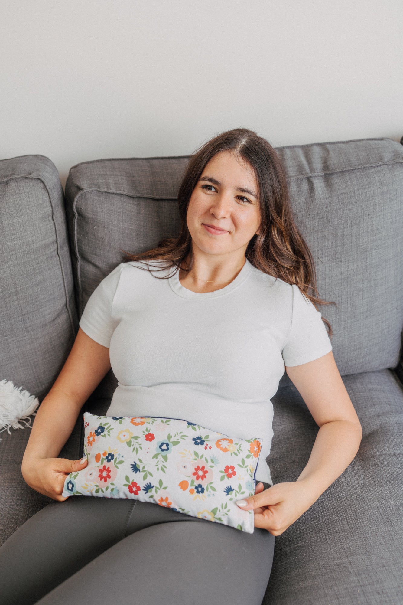 lady with navy floral microwavable heating pad on stomach to soothe cramps