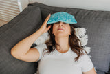 lady with blue and white floral eye pillow covering dry eyes 