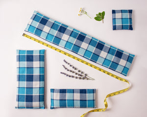 4 microwave heating pads/ice packs laid out to show the different sizes. Fabric is blue plaid flannel.