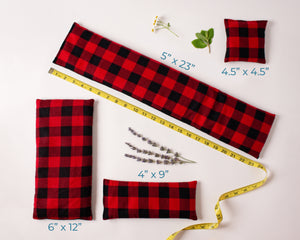 4 Whiffy Bean Bags, which are microwave heating pads/ice packs laid out to show the different sizes. Fabric is read and black buffalo plaid flannel fabric.