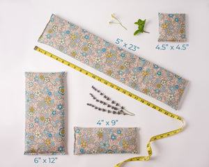 4 microwave heating pads/ice packs laid out to show the different sizes. Fabric is gray floral.